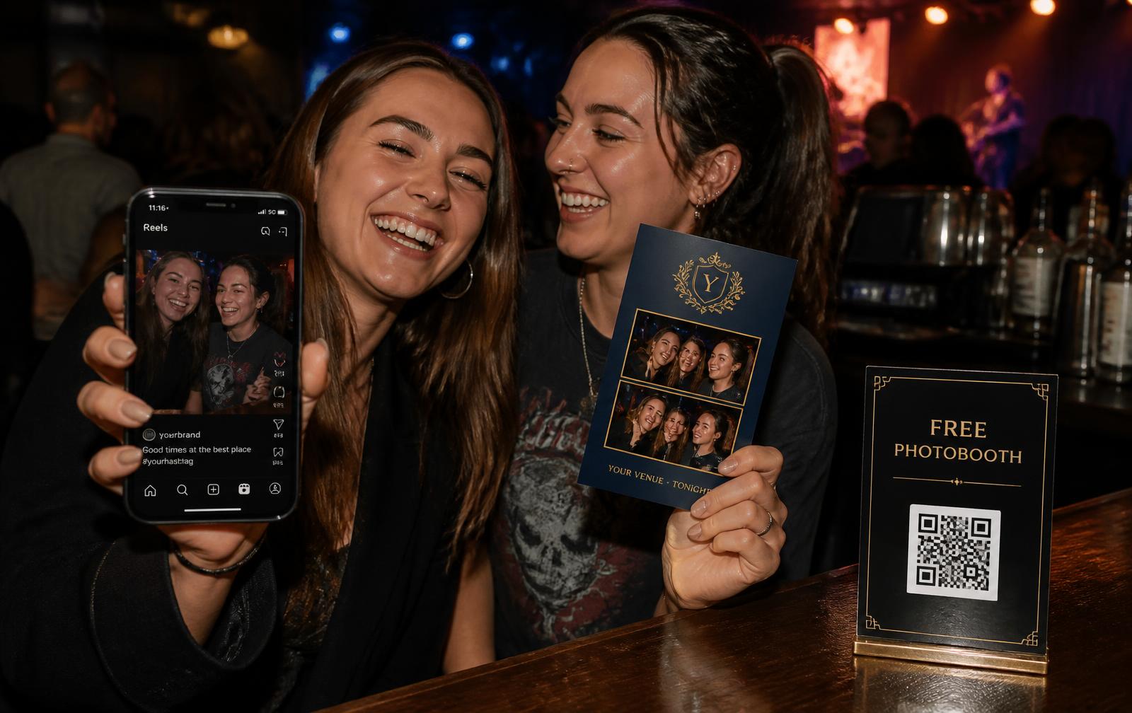 Two friends at the back bar of a music venue: one holds up her phone with the clip she just shared, the other a midnight blue branded photo postcard, next to a black “Free Photobooth” QR card